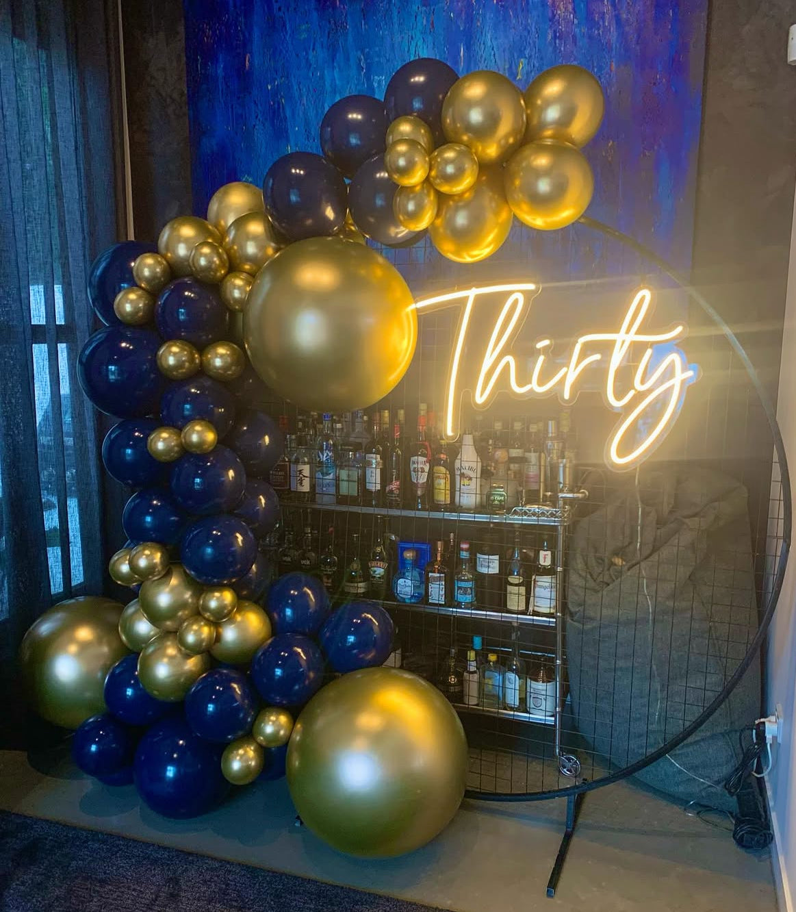 Black circular mesh backdrop with balloons and neon light on it