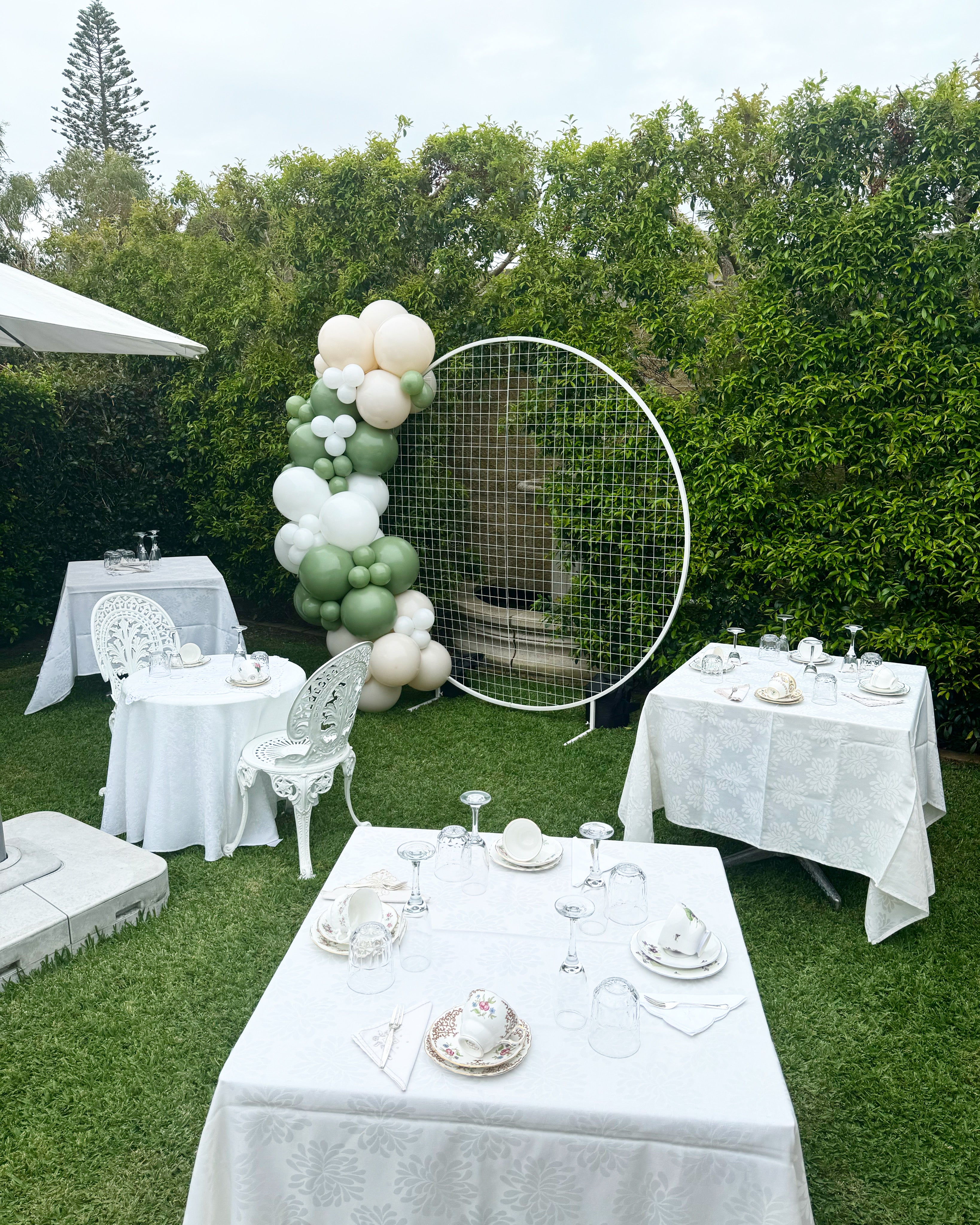 Circular mesh backdrop with white and green half balloon arch
