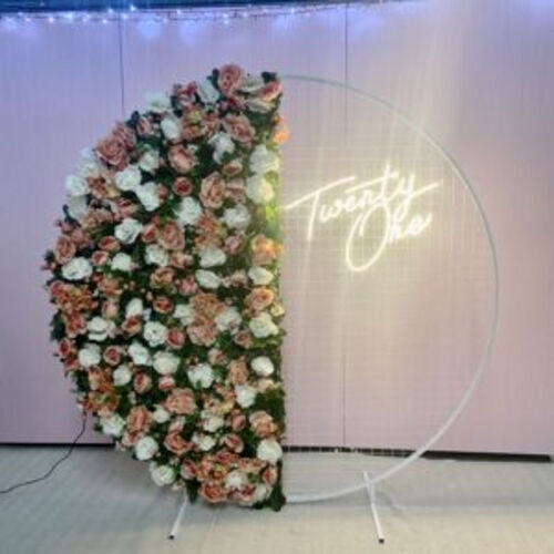 White mesh backdrop half covered in light pink, white, and greenery flowers