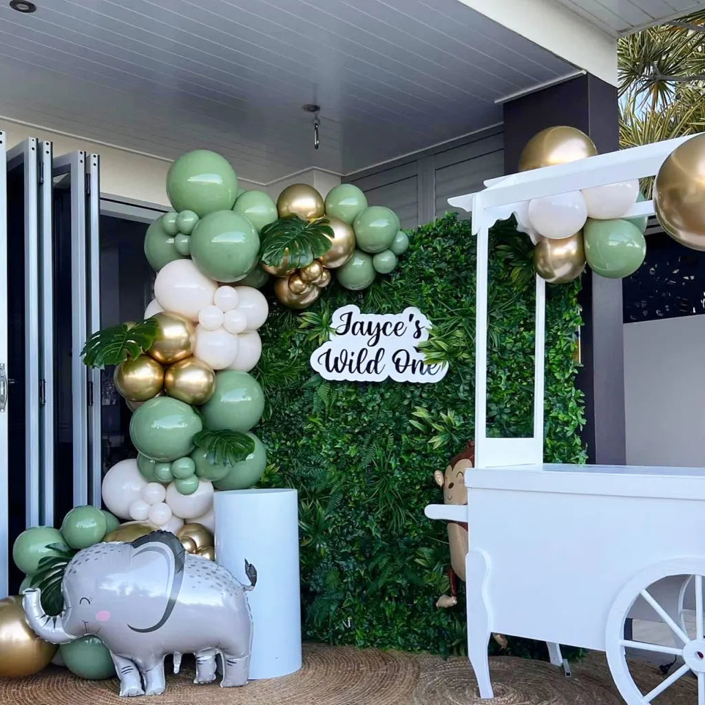 luxurious grass wall backdrop with signage and balloons